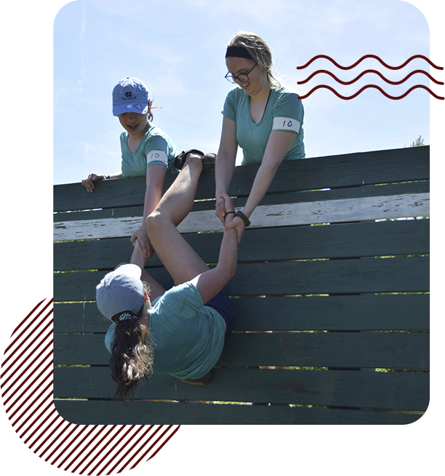 Scouts climbing an obstacle together.